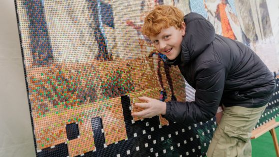 Lego Stonehenge with a young man adding a piece