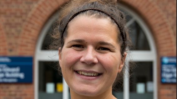 Charlotte Beaman-Evans standing outside the university in Worcester. She has dark hair, pulled back with a headband and smiles at the camera