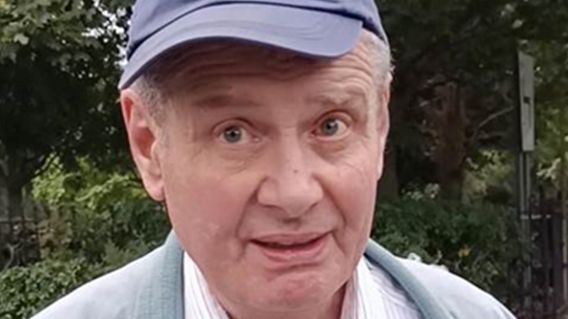 A man wearing a blue cap, white and red striped shirt and blue-grey jacket