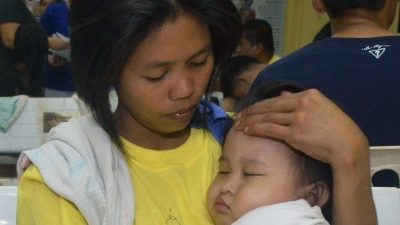 A woman holds her child in a hospital after they were rescued from a passenger vessel MV St Thomas Aquinas before it sank in Talisay, Cebu in central Philippines 17 August, 2013.