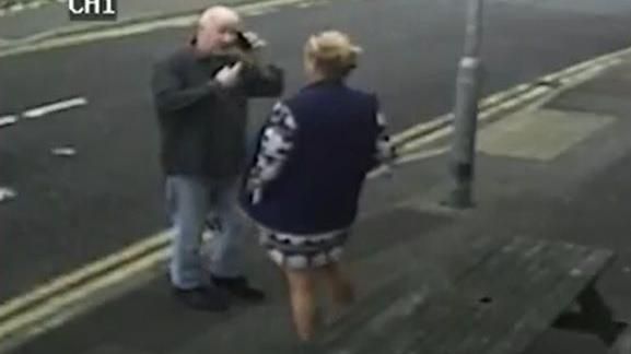 Stephanie Langley and Matthew Bryant on a pavement facing each other, he is on the phone
