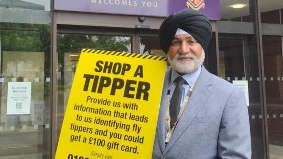 Councillor Bhupinder Gakhal holding a sign saying 'shop a tipper'