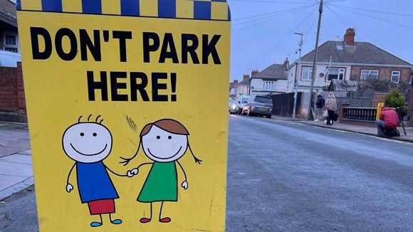 A sign warning parents about parking restrictions
