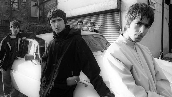 Oasis leaning against a Jaguar XJ6 car in Withington, Manchester, in 1993. L-R Paul McGuigan, Noel Gallagher, Tony McCarroll, Paul Arthurs (aka Bonehead) and Liam Gallagher.