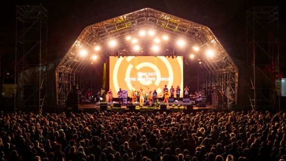 A stage lit up at WOMAD festival with the a big crowd facing the stage. Taken at night.