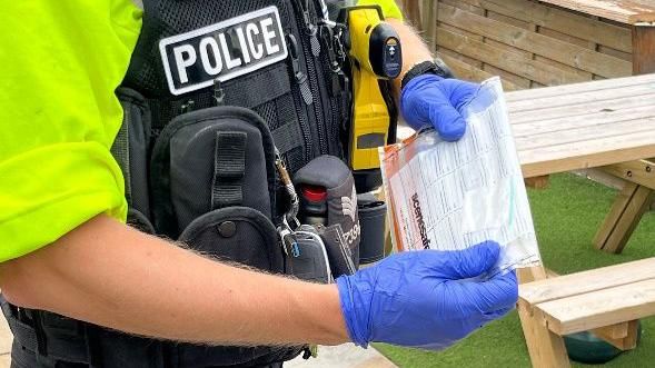 A police officer holding a bag of suspected illegal drugs