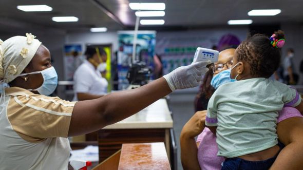 A woman takes the temperature of a child at Lagos airport, Nigeria