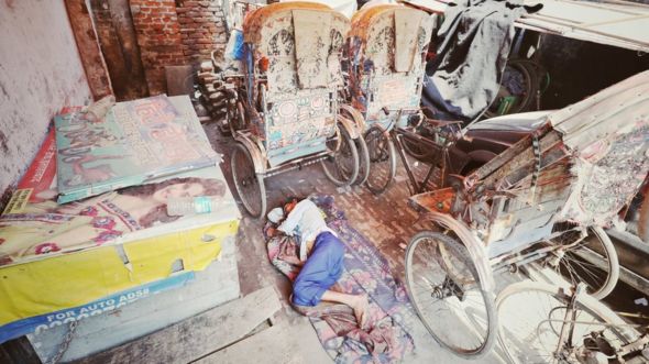 Kishan Lal lies next to his unused rickshaw
