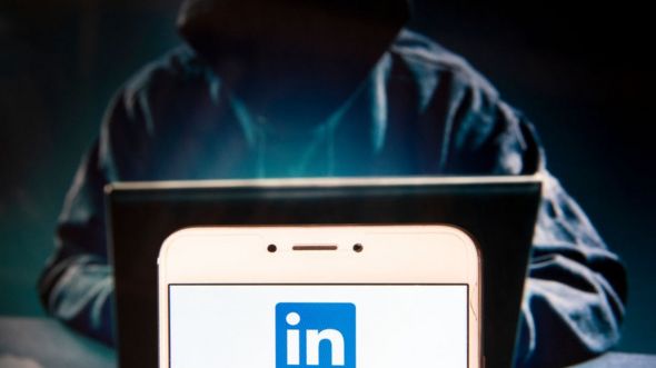 Persona encapuchada mirando una pantalla de una computadora y el logo de LinkedIn