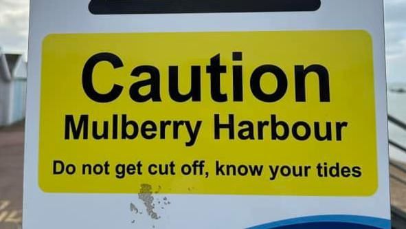 Close up of a warning sign at Thorpe Bay, Essex, saying Caution  Mulberry Harbour