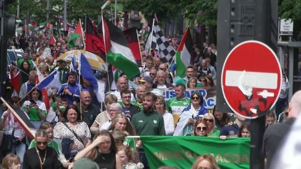 People flying green, red, white and blue flags in the street 