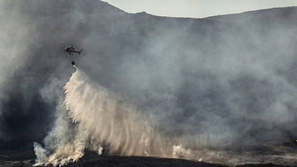 Helicopter releases water over hill fire