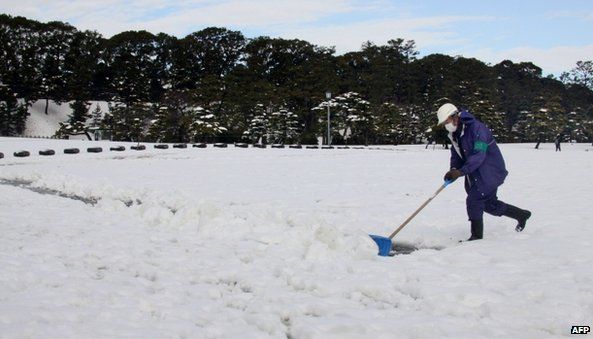 A man shovels snow to make a path at a park in Tokyo (9 February 2014)
