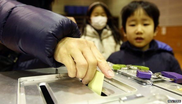 A woman casts her ballot at a polling station during the Tokyo gubernatorial election in Tokyo (9 February 2014)
