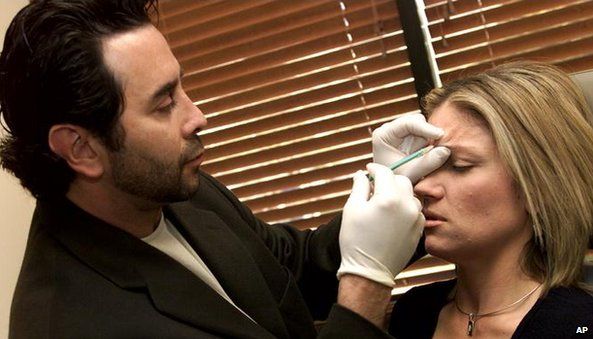 Man injecting Botox into woman's face