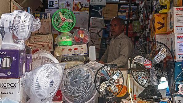 A shopkeeper selling table fans waits for customers at a market on a hot summer day in Varanasi on May 27, 2024