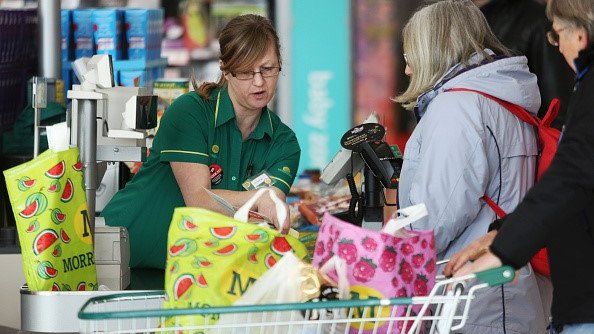 An employee speaks with a customer at the check-out inside a Morrisons supermarket