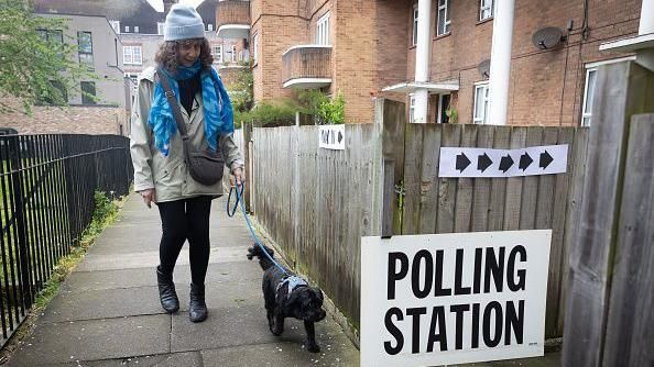 Woman walking a dog near a polling station sign