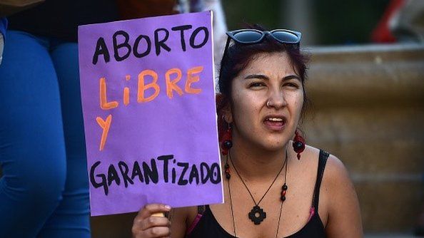 An activist holds a sign reading 'Free and guaranteed abortion' during a pro-abortion demo in front of La Moneda presidential Palace in Santiago on November 11, 2014