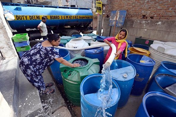 People filling water from a supply water tanker of Delhi Government, during a high temperature heat wave, at Sangam Vihar, on June 9, 2024 in New Delhi, 