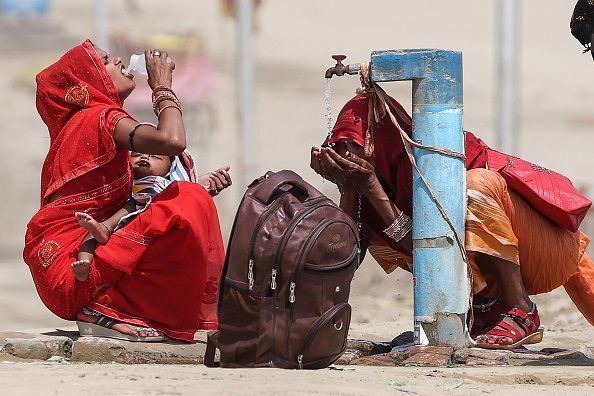 Women quench their thirst with the tap water on a hot summer afternoon during heatwave in Prayagraj on June 10, 2024