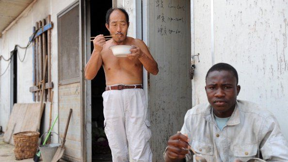 Workers from China and Burkina Faso employed by Sinohydro, a Chinese state-owned hydropower engineering and construction company, eat after returning to their dormitories at the end of a working day on January 31, 2012 in Bata.