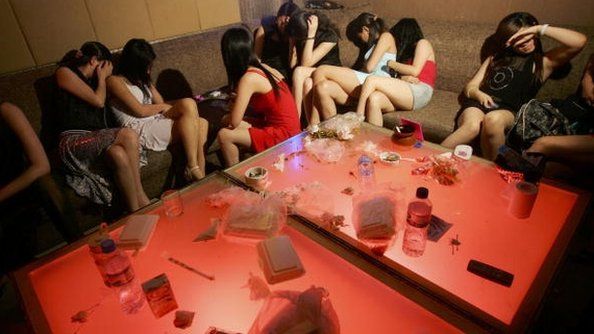 File photo: Women hide their faces as police raid an entertainment center which is suspected to have prostitution business on 21 June 2006 in Beijing, China