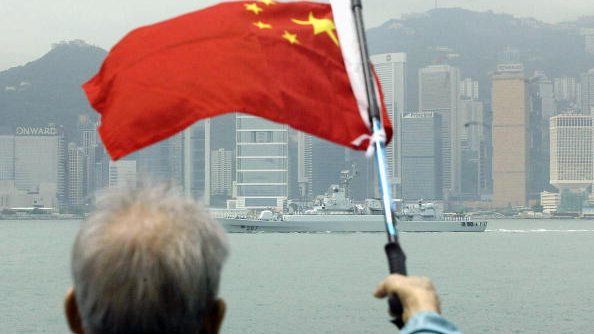 File photo: An elderly supporter waves a Chinese flag as a ship from a Chinese People Liberation Army Navy task group passes the Victoria harbour skyline in Hong Kong, 5 May 2004