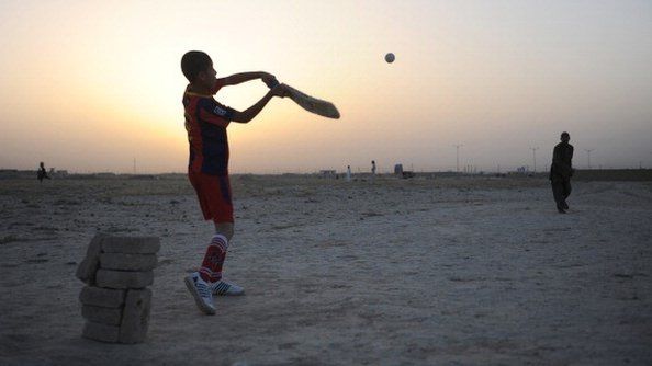 Young Afghans play cricket as dusk falls