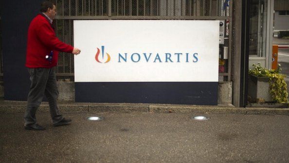 A man walking in front of a Novartis Logo
