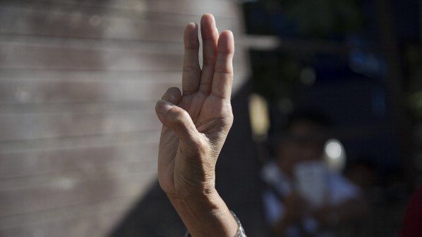 A woman flashes a three-finger salute during a gathering outside the Australian embassy on 4 June 2014 in Bangkok.
