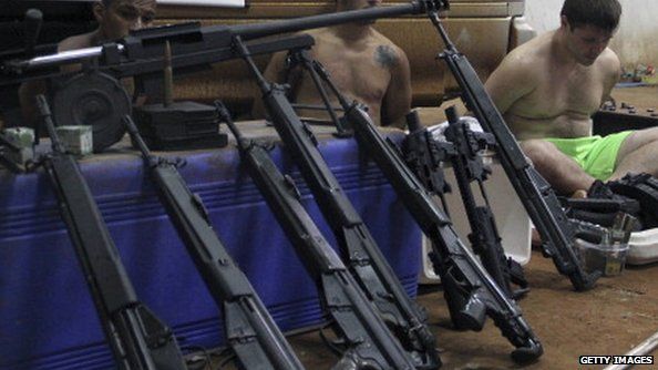 Brazilian nationals (L to R) Roberto Torres Gonzalez, Antonio Cesar Ibarra and Luis Fernando Cabral and weapons--assault rifles and a caliber 50 sniper rifle-- seized during an operation are presented to the press, in Ciudad del Este on February 7, 2014.