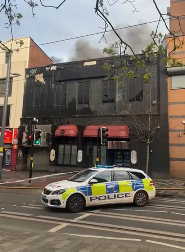 Smoke rising from the building, with a police car in front of the cordon