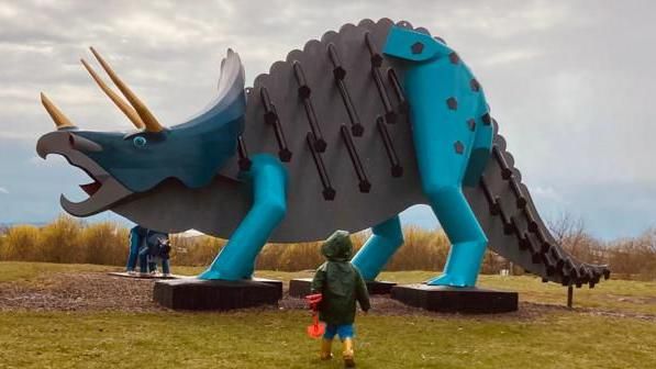 Child approaches giant steel dinosaur