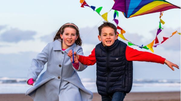 A boy and a girl flying a kite on Redcar beach