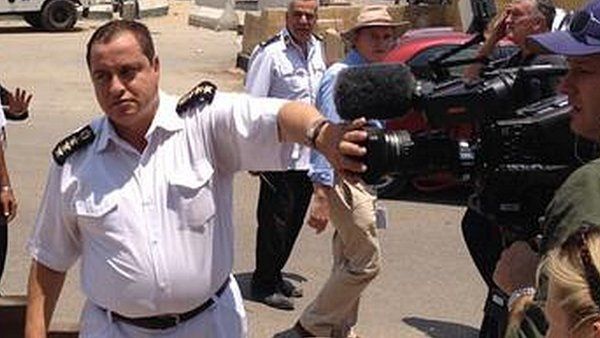 Egyptian policeman covers camera lens as BBC crew films outside Torah Prison