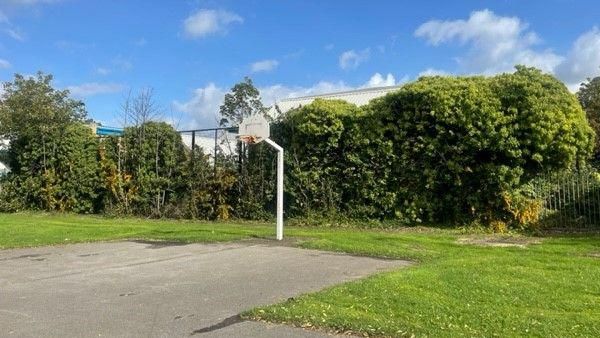 A derelict games area in East Park, with a concrete court and a basketball net