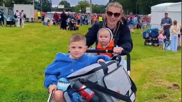 A woman and her children arrive at the festival site with bags and a pushchair