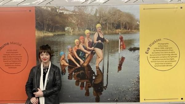 A woman in front of a billboard of swimmers