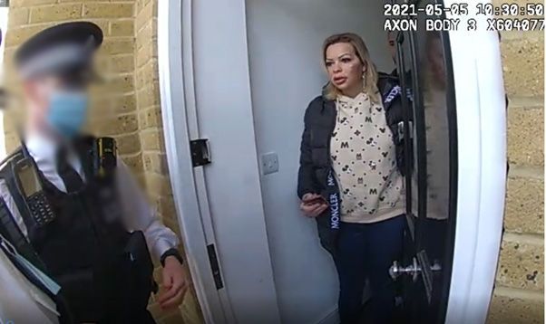 A still from police bodycam footage in 2021 showing Nikolova opening the door to an officer, whose face is blurred and who is wearing a medical mask