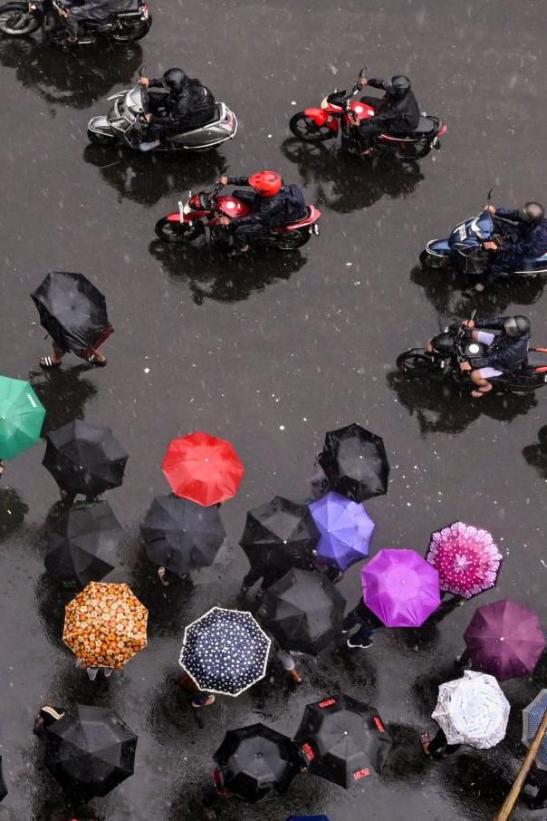 Commuters wait with umbrellas for transport in Kolkata, India