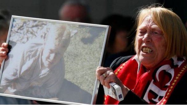 A relative holds up a photo of Keith McGrath, who died in the Hillsborough disaster, outside the Hillsborough Inquest in Warrington