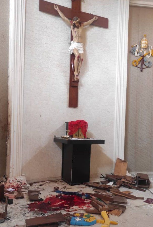 A Christian cross with things scattered on the floor around it