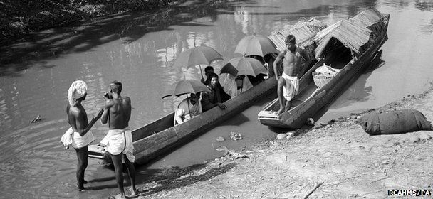 A group seated in two ferry canoes moored in a stream at an unknown location in India at least a century ago