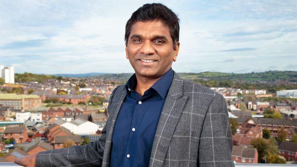 Dr Chandra Kanneganti pictured with his arm resting on a barrier as he smiles at the camera with buildings in the background.