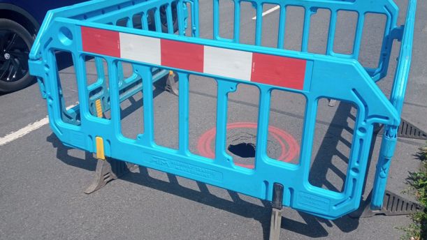 Small sinkhole surrounded by safety barriers