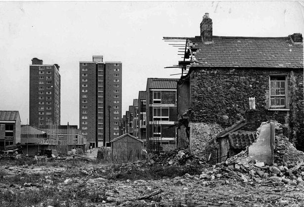 Half-demolished terrace house with tower blocks in the background