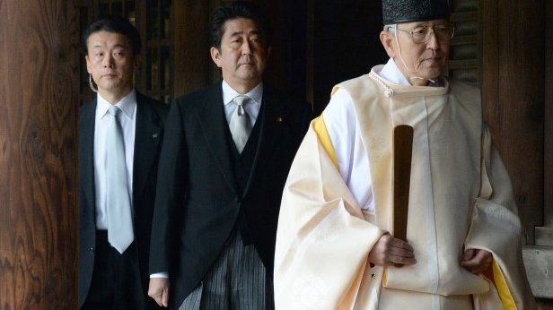 A Shinto priest (R) leads Japanese Prime Minister Shinzo Abe (C) as he visits the controversial Yasukuni war shrine in Tokyo on December 26