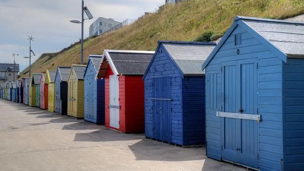 A row of colourful beach huts on Sheringham East Promenade
