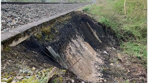 The side of a train track showing fresh dark earth and a gap near the line